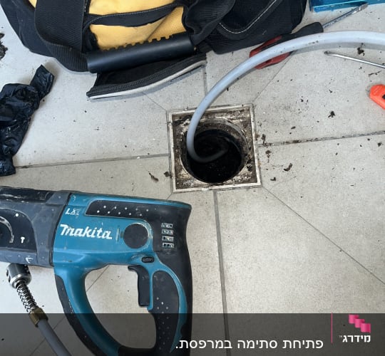 פתיחת סתימה בקופסת ניקוז ברצפה באמצעות מכונה חשמלית
